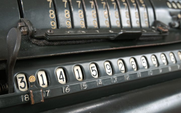 An eighth grade student reviewing math notes and a calculator at a wooden school desk.