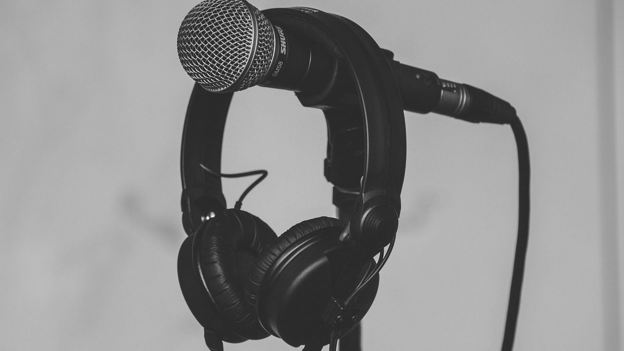 A multi-device audio desk setup featuring laptops, an audio interface, and a professional microphone.