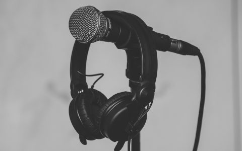 A multi-device audio desk setup featuring laptops, an audio interface, and a professional microphone.