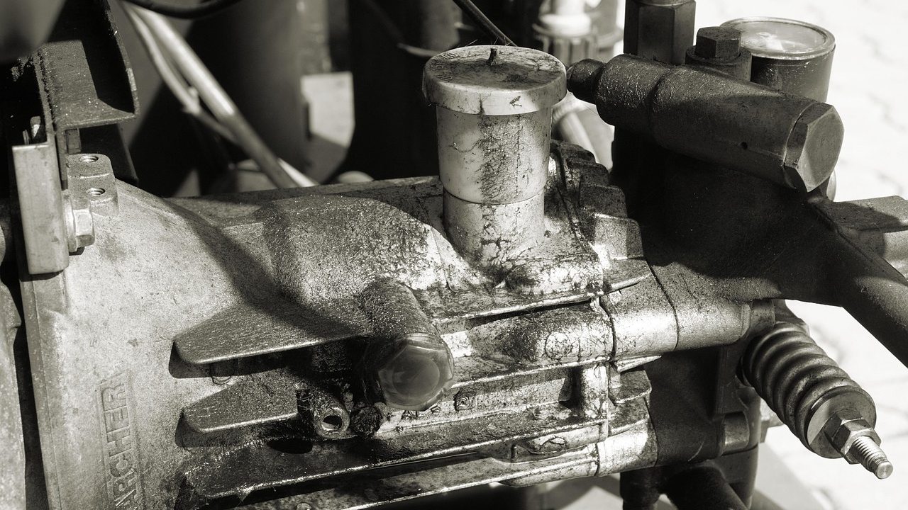 A service technician examining the mechanical compressor compartment behind a modern kitchen refrigerator.