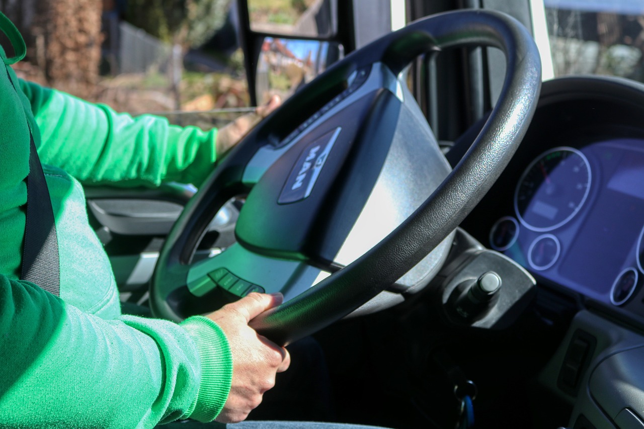 Driver behind the steering wheel navigating a vehicle on a public road.
