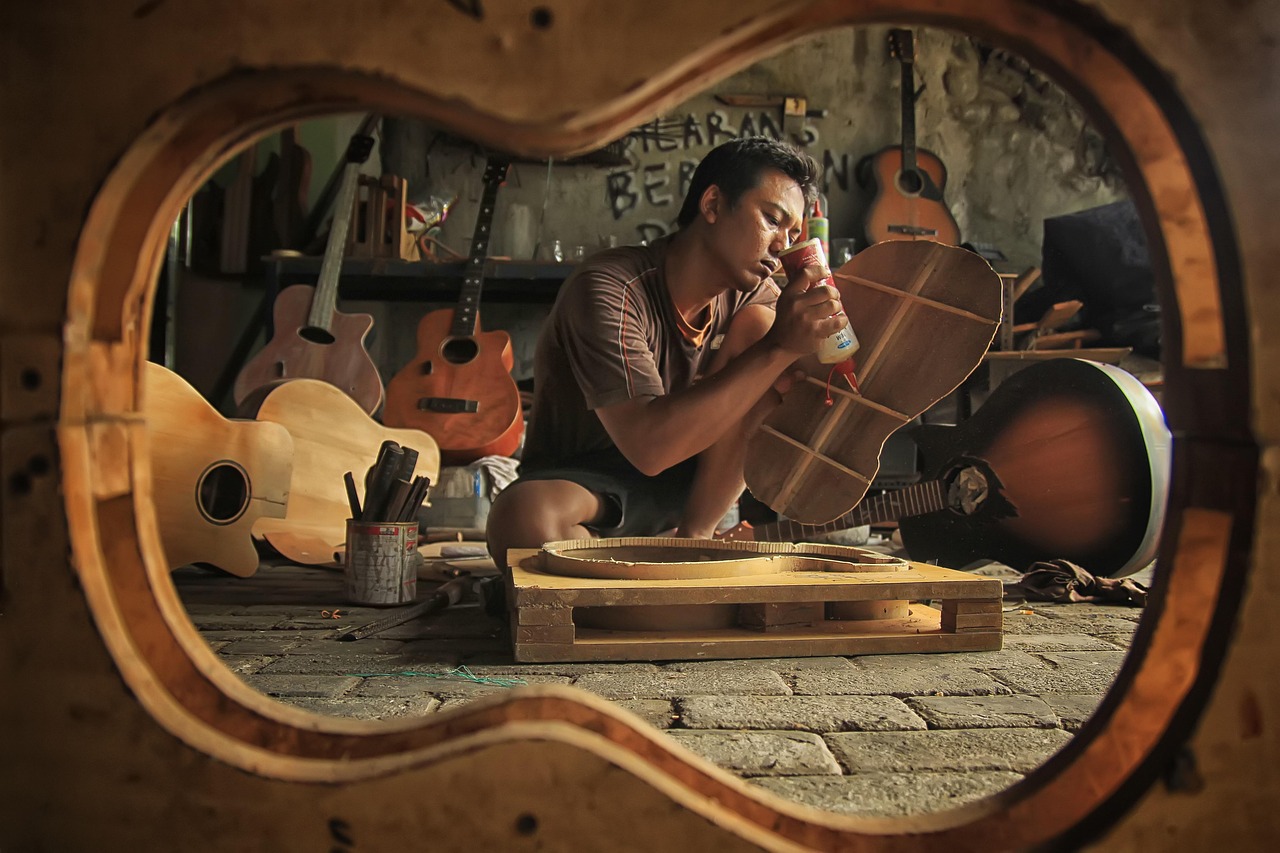 A technician performing a professional setup on a guitar at a workshop bench