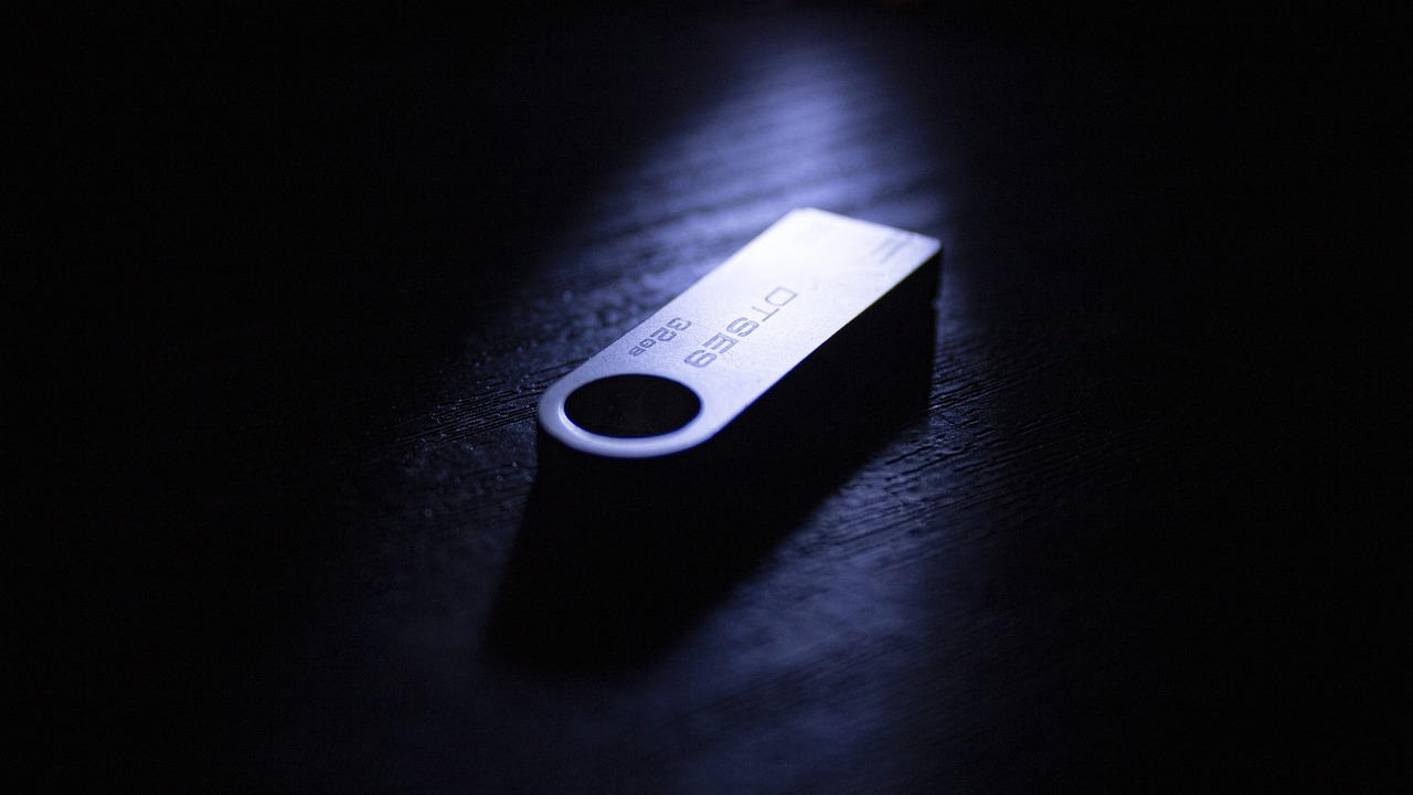 Compact desktop computer and external drive on a warm dark wood surface.