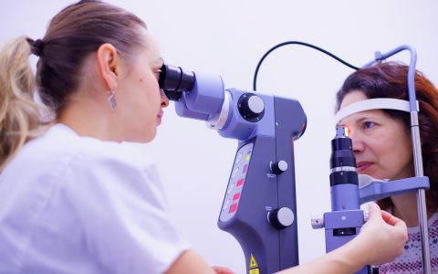 Child receiving a comprehensive eye examination from an optometrist in a bright clinic setting.