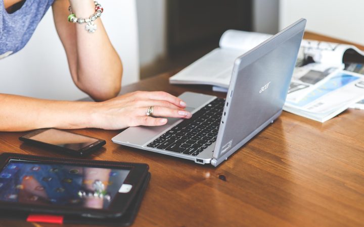 A professional typing notes on a laptop keyboard at a wooden desk.
