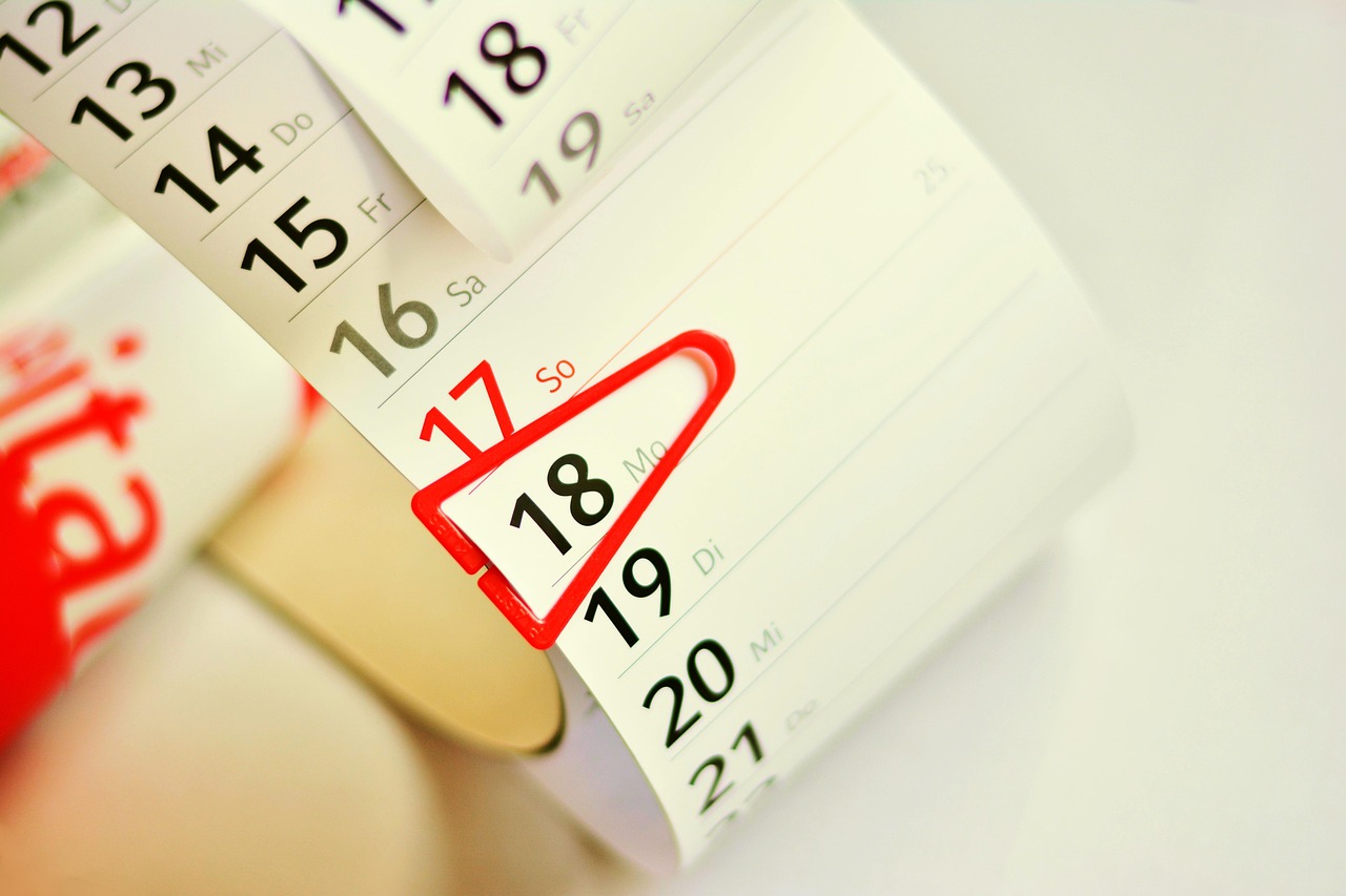 An individual reviewing written notes and a calendar schedule at a table.