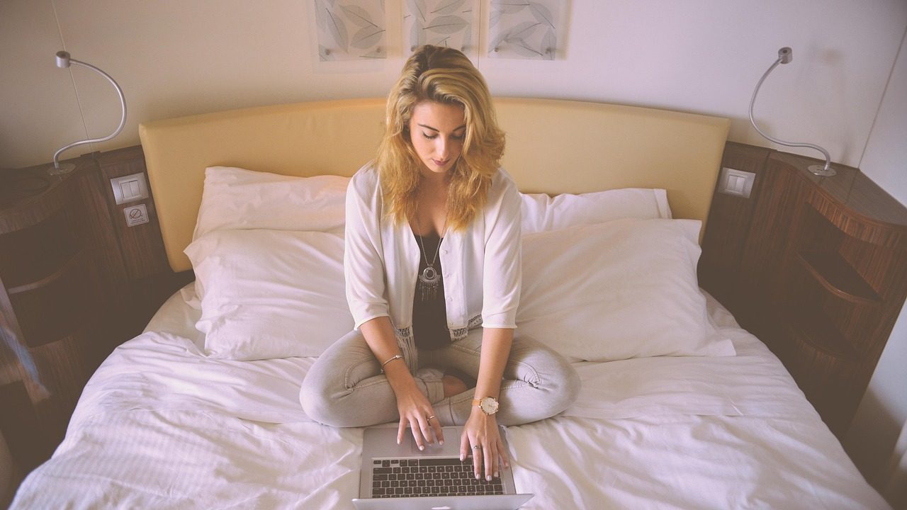 A remote worker typing on a laptop keyboard at a wooden desk.