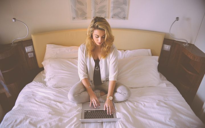 A remote worker typing on a laptop keyboard at a wooden desk.