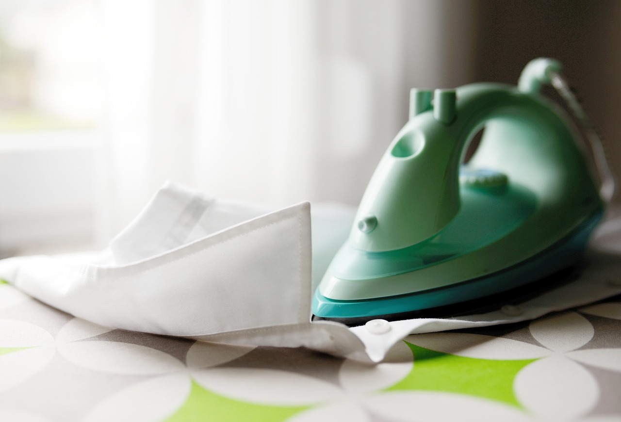 A traditional ironing board set up in a bright apartment bedroom.