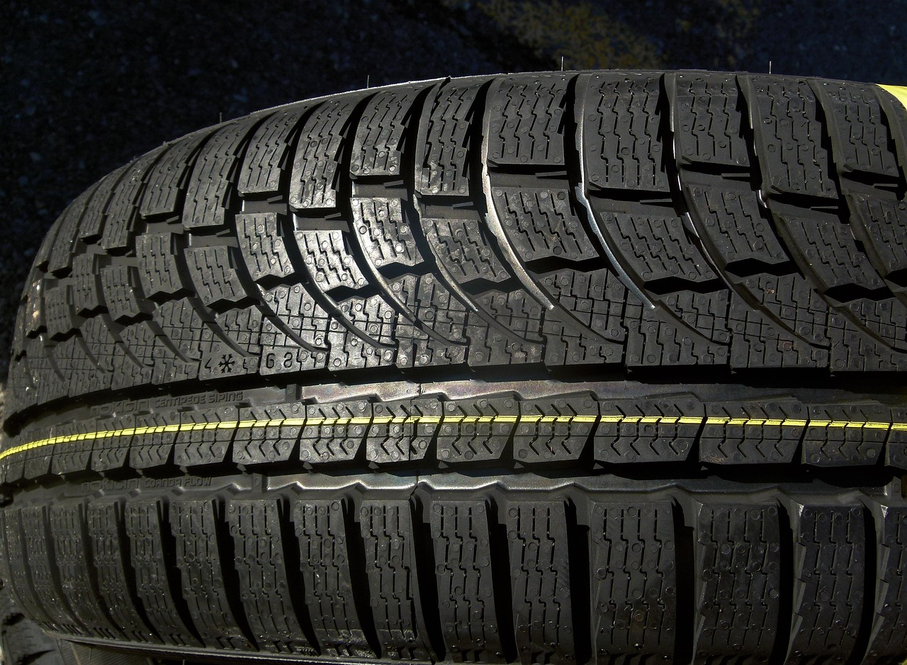 Certified auto mechanic checking tire wear and performing routine maintenance on a vehicle in an independent service garage.