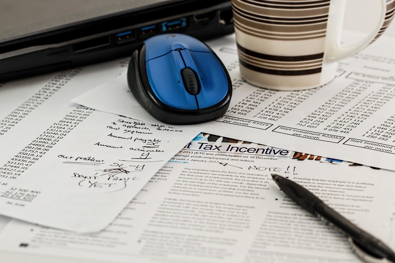 Tax documentation and diagnostic psychological evaluations arranged neatly on a desk next to a calculator.