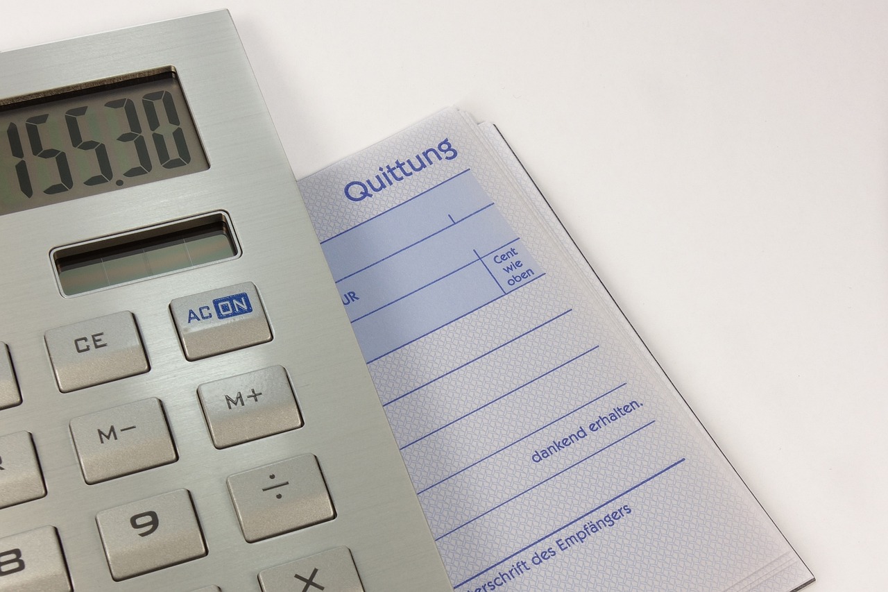 Close-up of a residential utility bill audit workspace with invoice, calculator, pen, and financial planning spreadsheet.