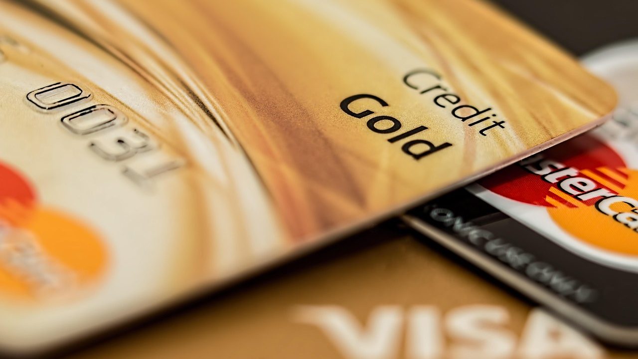A modern leather wallet and credit cards next to an open quarterly spending calendar on a bright wooden desk.