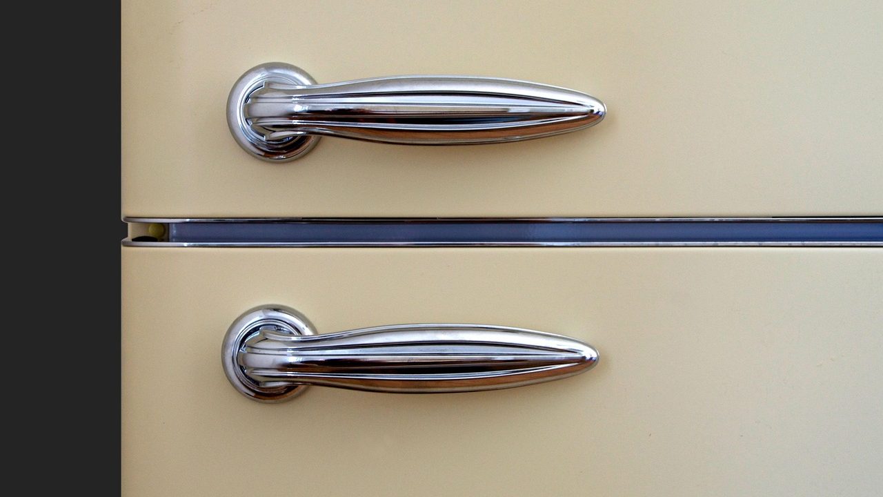 Digital multimeter probes testing electrical continuity on a metal refrigerator defrost heater element inside a freezer.