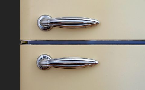 Digital multimeter probes testing electrical continuity on a metal refrigerator defrost heater element inside a freezer.