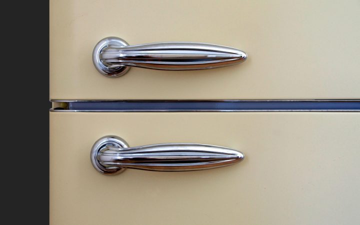 Digital multimeter probes testing electrical continuity on a metal refrigerator defrost heater element inside a freezer.