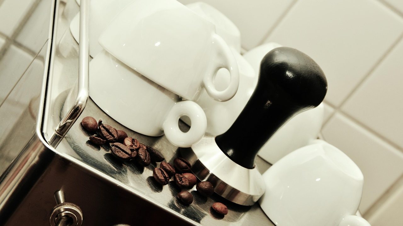A refurbished dual-boiler commercial espresso machine open on a workbench undergoing technical testing and boiler inspection.