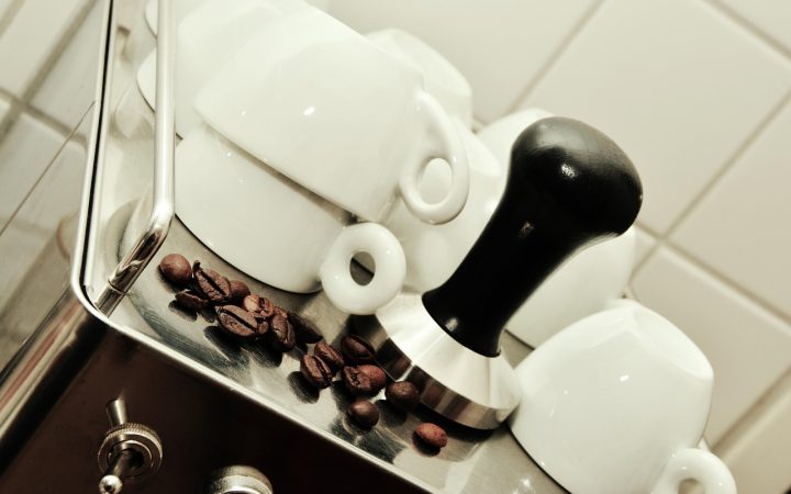 A refurbished dual-boiler commercial espresso machine open on a workbench undergoing technical testing and boiler inspection.
