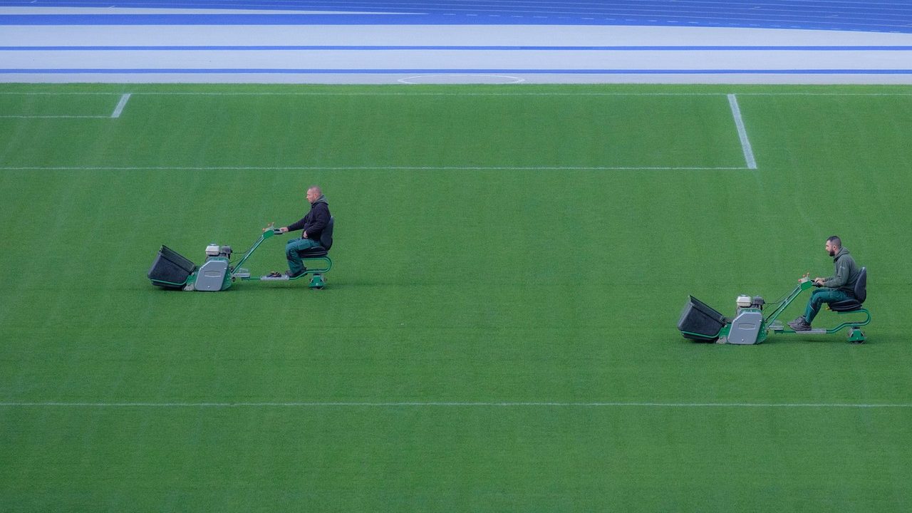 Homeowner inspecting the deck of a cordless electric lawn mower in a suburban garage