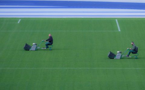 Homeowner inspecting the deck of a cordless electric lawn mower in a suburban garage