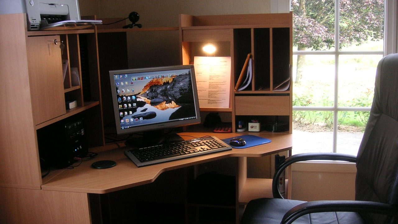 Compact monochrome laser printer resting on a wooden home office desk next to a laptop.