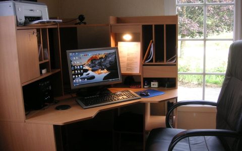 Compact monochrome laser printer resting on a wooden home office desk next to a laptop.