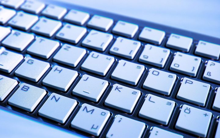 Close-up of hands typing on a modern mechanical keyboard at a wooden desk.