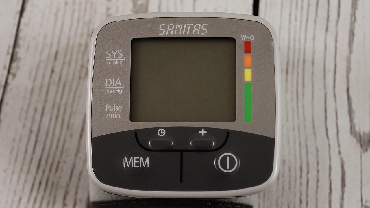 A digital blood pressure monitor and pulse oximeter resting on a clinical table during a quality verification test.