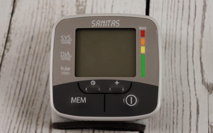 A digital blood pressure monitor and pulse oximeter resting on a clinical table during a quality verification test.