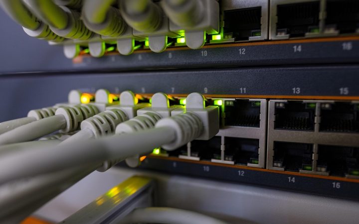 Close-up of a person plugging an Ethernet cable into a modern white router.
