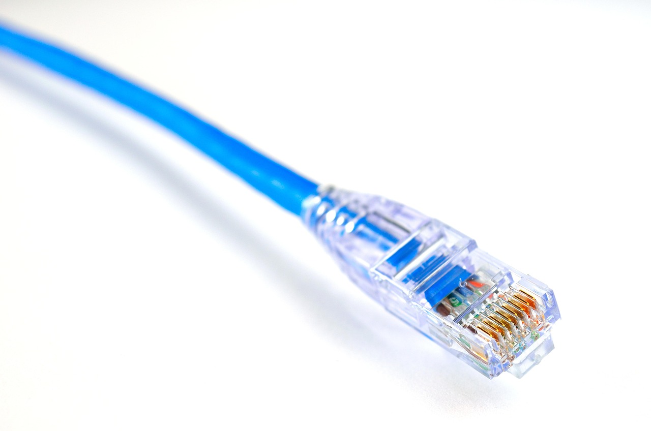 Close-up of an Ethernet cable being plugged into a local network video recorder panel.