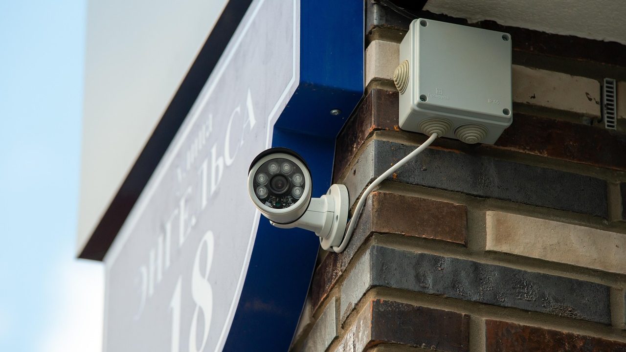 A refurbished smart security camera positioned beside a local NVR storage drive on a clean wooden desk.