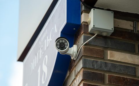 A refurbished smart security camera positioned beside a local NVR storage drive on a clean wooden desk.