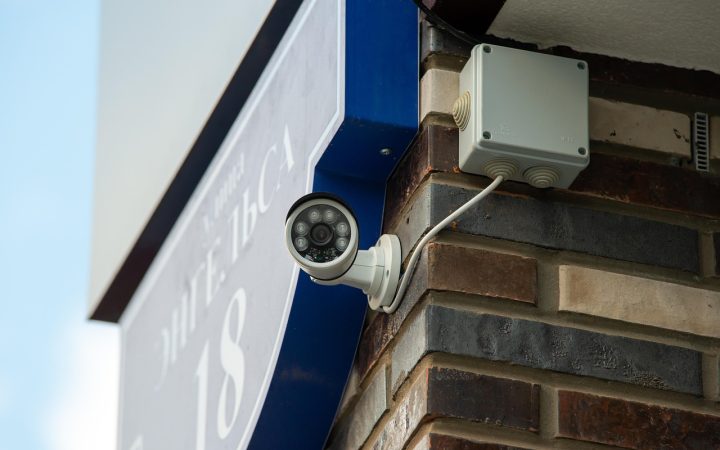 A refurbished smart security camera positioned beside a local NVR storage drive on a clean wooden desk.