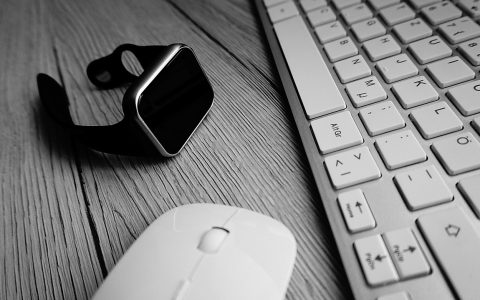 Close-up of a person inspecting a smartwatch on a clean desk