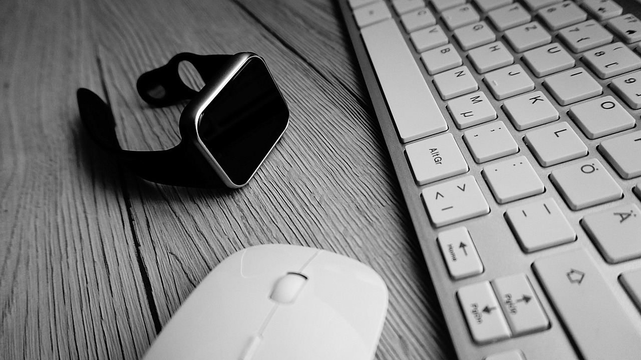 Close-up of a person inspecting a smartwatch on a clean desk