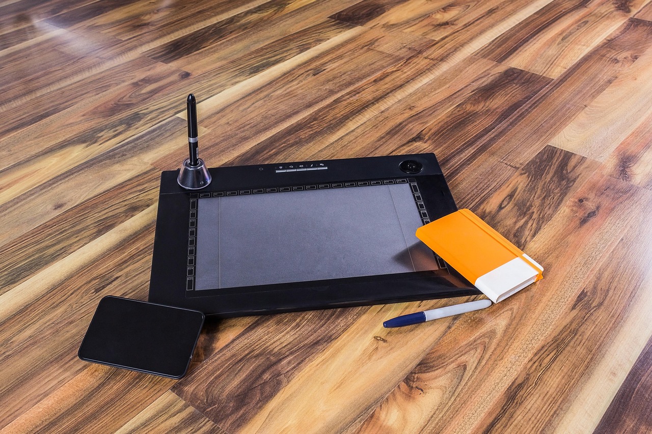 Artist using a stylus to draw on a tablet screen.
