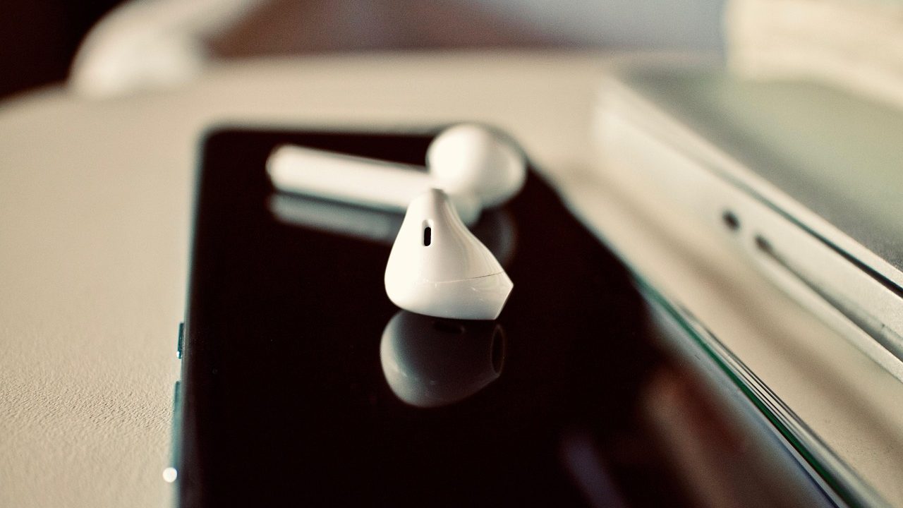 Close-up of a consumer holding a charging case and wireless earbuds for inspection