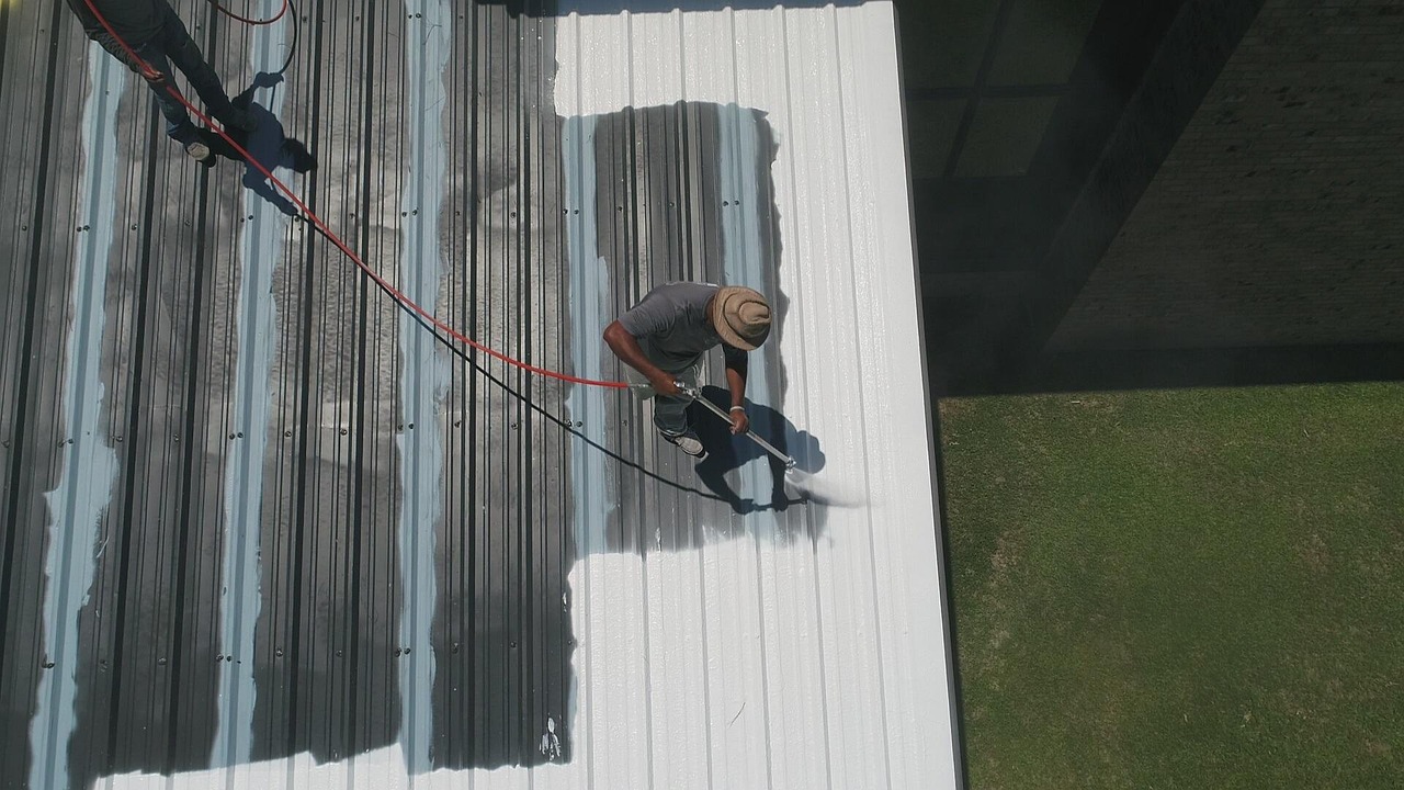 A home inspector checking metal flashing around a brick chimney on an asphalt shingle roof.
