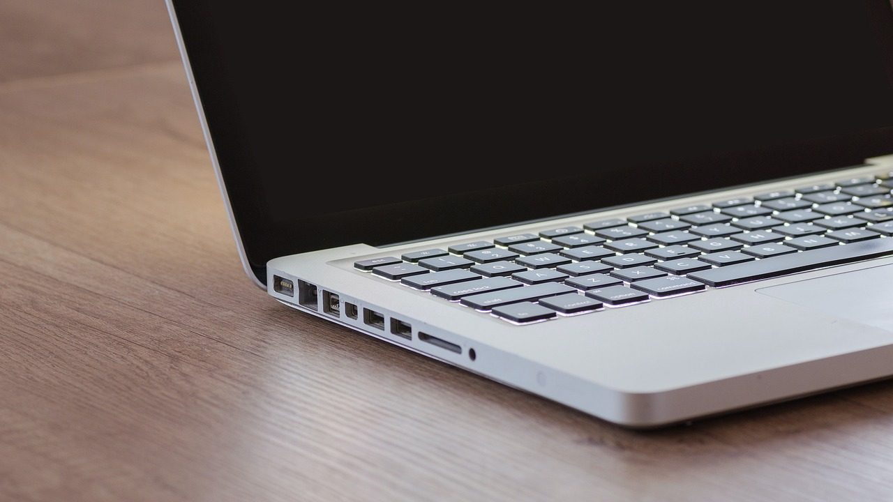Network attached storage device on a clean wooden desk beside a laptop used for remote work