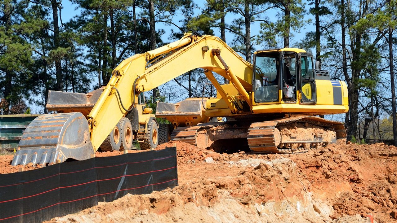 Backhoe excavator parked near an open soil trench during a residential septic system inspection.