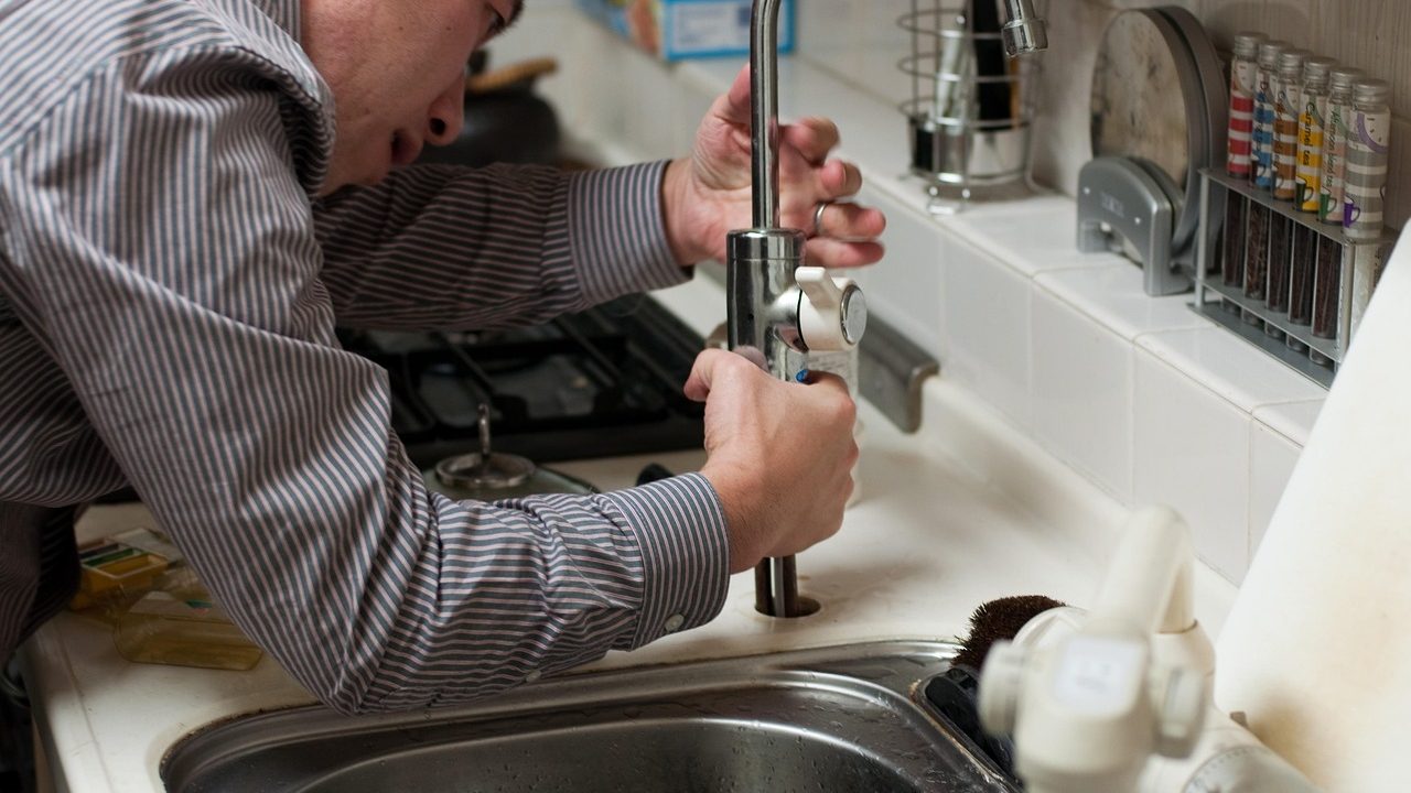 Plumber holding tools while working on an exposed shower mixing valve