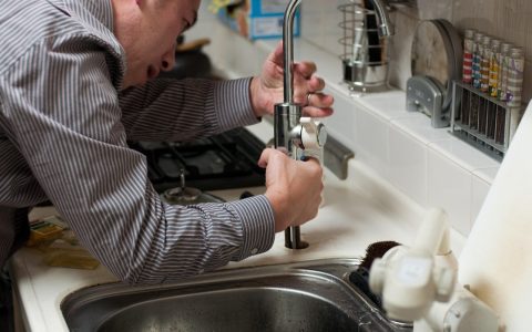 Plumber holding tools while working on an exposed shower mixing valve