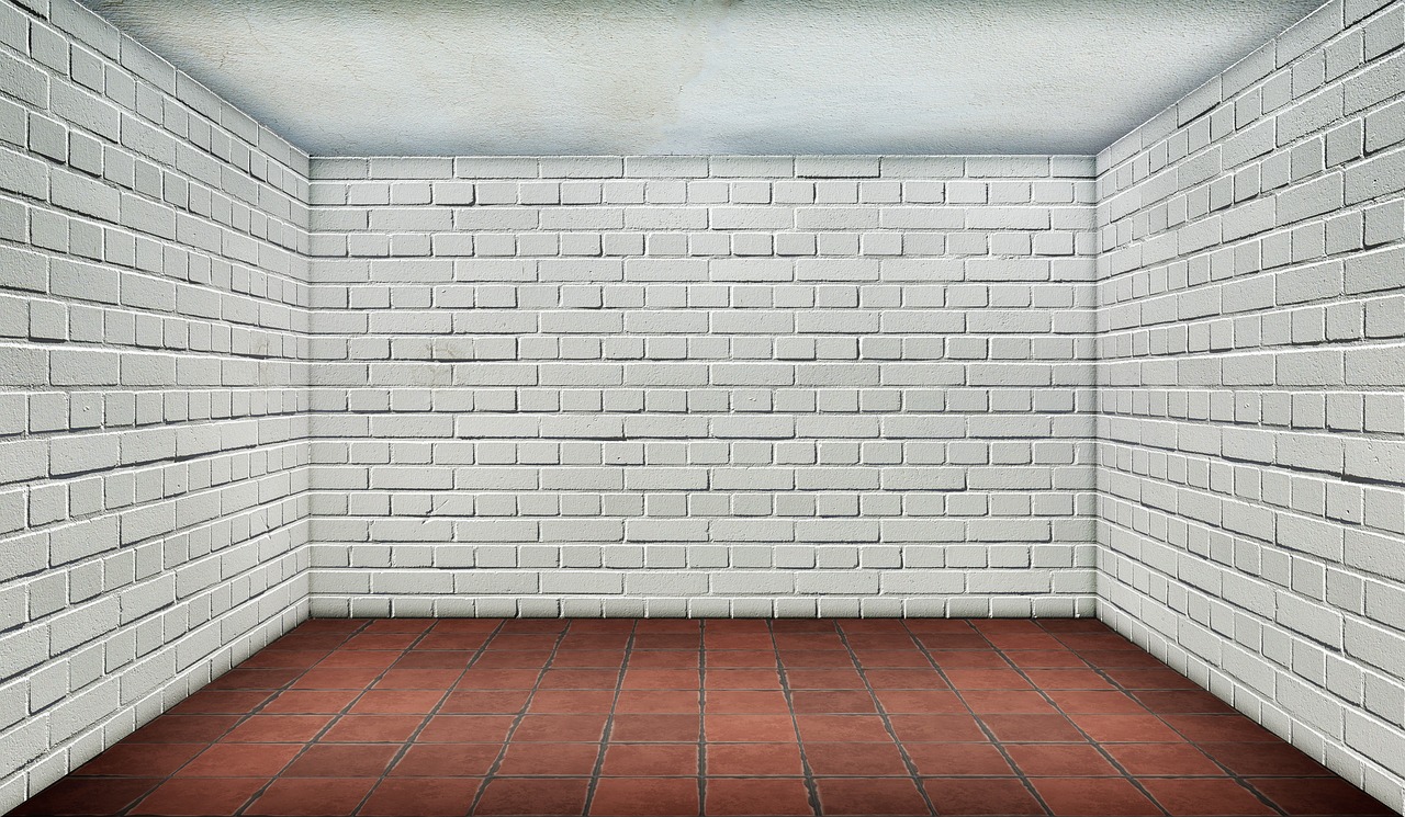 A wireless room temperature sensor mounted on a wall near a ceiling supply vent in a bright home office.