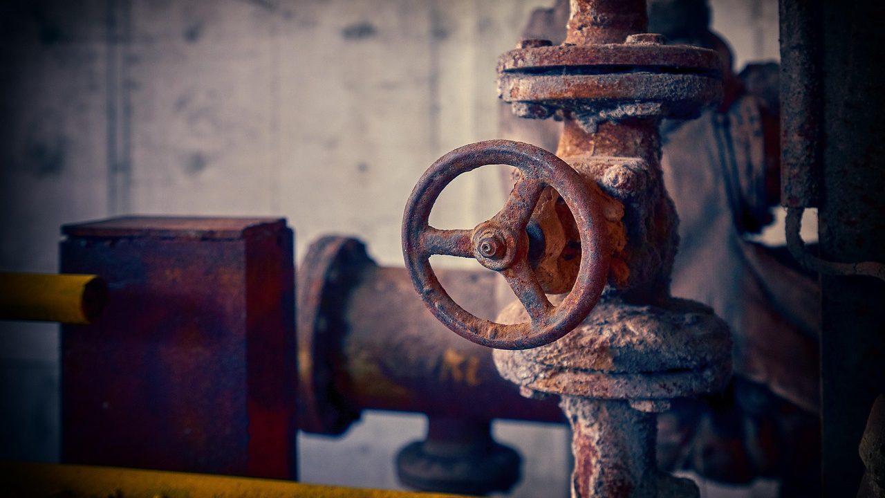Plumber working on a main water line shut-off valve installation.