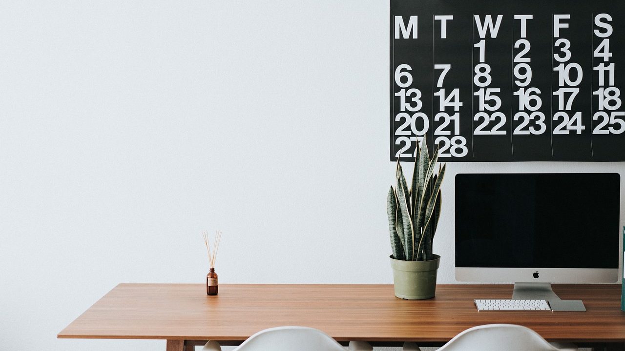 A modern corporate desk setup with payroll spreadsheets and leave calendar documents.