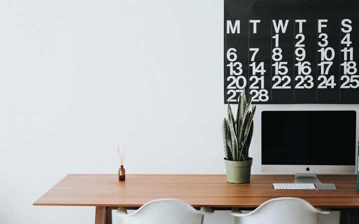 A modern corporate desk setup with payroll spreadsheets and leave calendar documents.