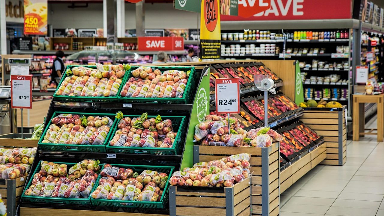 A shopper browsing grocery store shelves filled with various packaged foods.