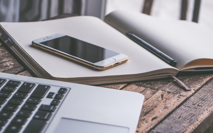 Parent organizing summer camp schedules and finances on a laptop and paper calendar at home.