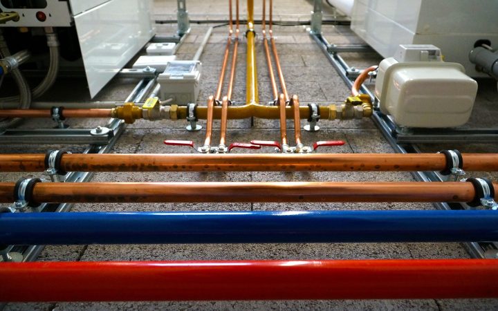 Open residential tankless water heater revealing internal plumbing components and wiring